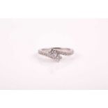 A 14k white gold and diamond crossover ring, set with two round brilliant-cut diamonds of