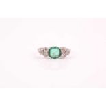 A platinum, diamond, and emerald ring, set with a cushion-cut emerald, approximately 7 x 7 mm,