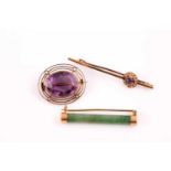 A single stone amethyst brooch; the circular cut amethyst in collet mount within a three band