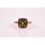 A peridot and diamond cluster ring, the cushion shaped peridot within a diamond border; to a 9ct