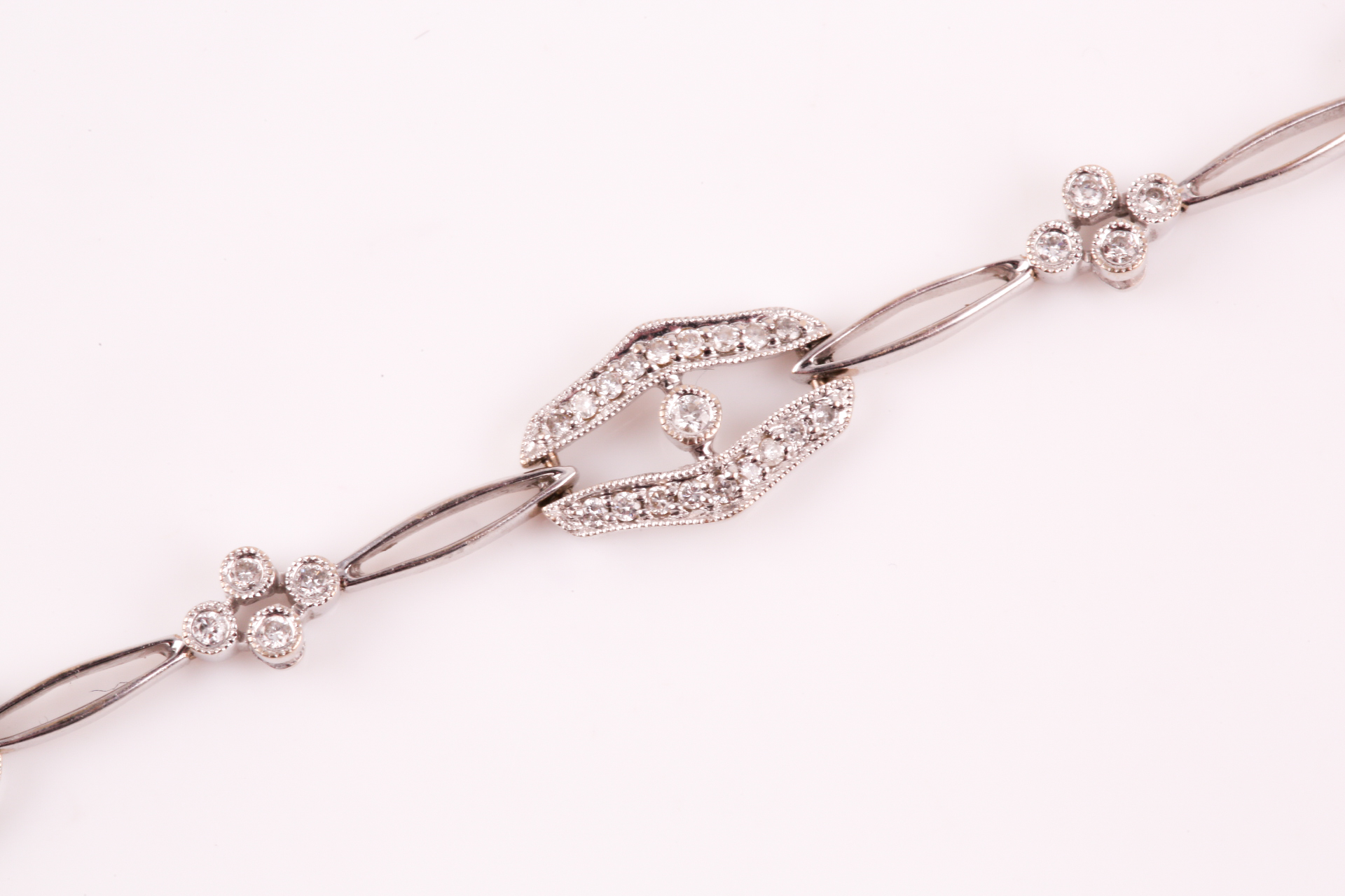 A diamond bracelet; of alternating diamond set openwork lozenge and four stone diamond clusters - Image 10 of 14