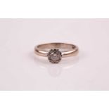 A single stone diamond ring; the round brilliant cut diamond claw mounted within an illusion