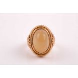 A yellow metal and onyx ring, the pale green cabochon onyx collet-set, with applied filigree