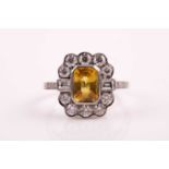 A platinum, diamond, and yellow sapphire ring, set with an emerald-cut sapphire of approximately 2.