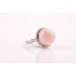 A diamond and coral cocktail ring, set with a rounded piece of angel coral, within a border of round