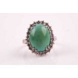 A diamond and turquoise cluster ring, set with an oval cabochon turquoise, within a border of
