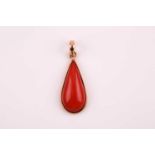 An 14ct yellow gold and coral drop pendant, set with a smooth pear-shaped coral, suspension loop
