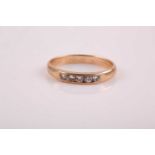 A small yellow metal and diamond ring, channel-set with five round brilliant-cut diamonds, bearing
