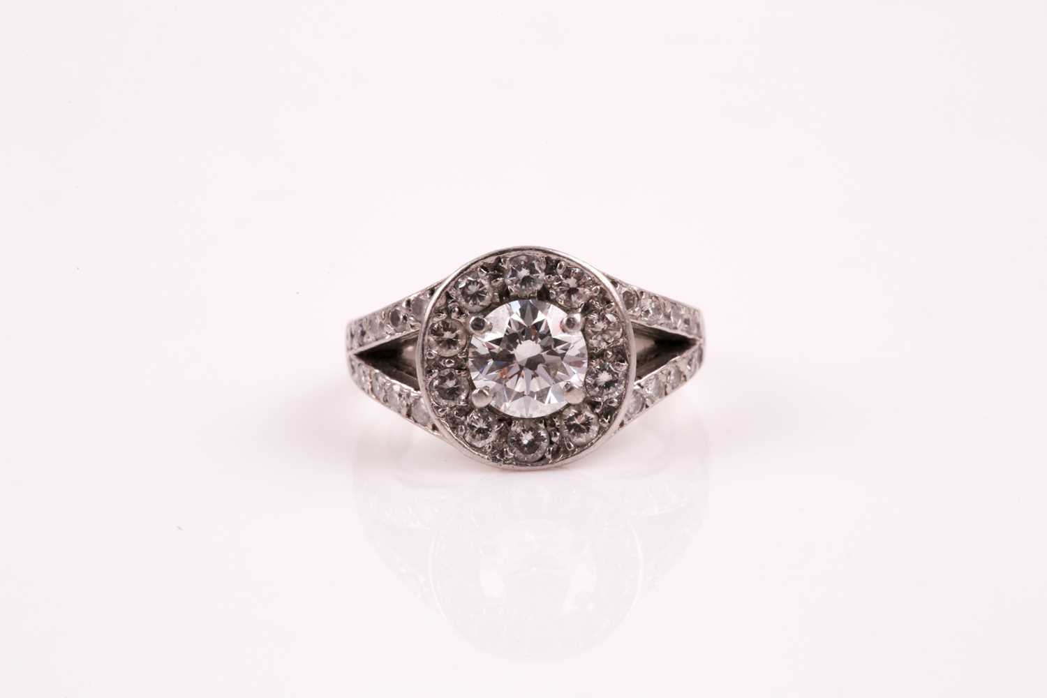 A diamond cluster ring, the central brilliant cut diamond in four claw mount above a channel set