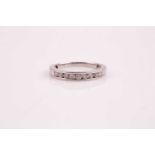 A nine stone half hoop eternity ring; the channel set round brilliant cut diamonds, in precious