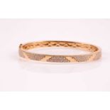 An 18ct yellow gold and diamond bracelet; the polished bangle with pave set round brilliant cut