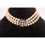 A triple strand pearl choker necklace, fastened with a yellow metal and silver-set diamond clasp,