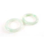A near pair of Chinese jade bangles, each mottled light green stone with apple green inclusions,