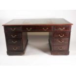 An early 20th century mahogany twin pedestal kneehole desk with an inset leather top over three