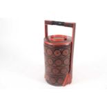 A 20th century Burmese red and black lacquered, cylindrical, ceremonial wedding food box with four