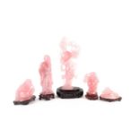 A group of Chinese rose quartz carved deities, Peoples Republic period, each on a carved wood stand,