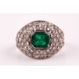 An emerald and diamond bombe ring, set with a square emerald-cut emerald, measuring approximately