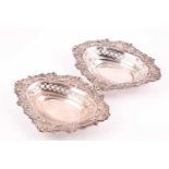 A pair of silver bonbon dishes. London 1900 by William Comyns; shaped oval with scroll chased and
