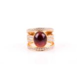 An 18ct yellow gold, diamond and garnet cocktail ring, centred with a rubover-set cabochon garnet,