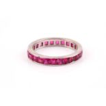 A white metal and ruby eternity ring, channel-set with mixed square-cut synthetic rubies, shank