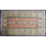 A 20th century Turkish rug with diamond lozenges on a muted red ground within broad borders and