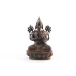 A Tibetan patinated and gilt bronze figure of a Gelpuga Lama seated with flowers about his arms