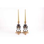 A pair of bronze and ormolu Empire style candlesticks, tri-angular in form with scrolled stylised