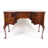 An early 20th century desk, having a well figured quarter veneered top with crossbanded border,