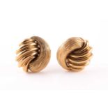 A pair of yellow metal earrings, of stylised knotted form, with lobed and textured segments,