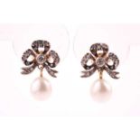 A pair of diamond and pearl drop earrings, the silver set gold-backed bow-shaped mounts inset with