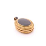 A Victorian gilt metal and black enamel locket, the case with a plain black enamel oval to centre,