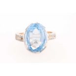 A diamond and blue topaz dress ring, set with a mixed oval-cut topaz, measuring approximately 16 x