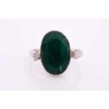An 18ct white gold, diamond, and emerald ring, set with a low grade mixed oval-cut emerald flanked