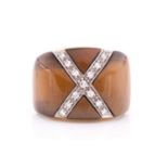 A yellow metal, diamond, and tigers eye cocktail ring, the wide band inset with a diamond-set cross,