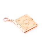 A yellow gold pendant in the form of a book, the hinged cover with quatrefoil decoration, opening to