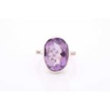 An 18ct white gold and amethyst ring, set with a mixed oval-cut amethyst, with diamonds set to the
