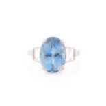 A diamond and blue topaz ring, set with a mixed oval-cut topaz, measuring approximately 12 x 8.5 mm,