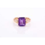 A yellow metal, diamond, and amethyst ring, set with an emerald-cut amethyst, measuring