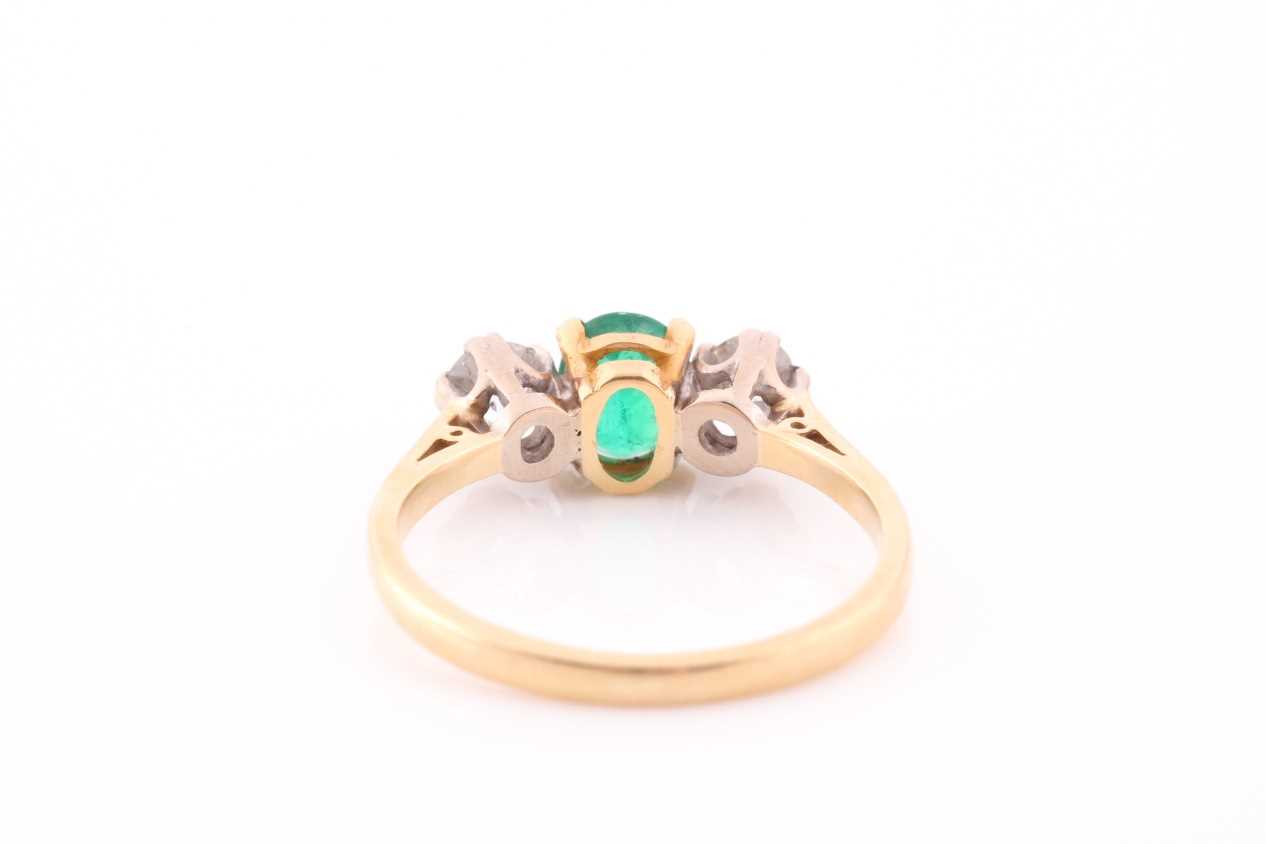A three stone half hoop emerald and diamond ring. The oval cut emerald in four claw mount flanked by - Image 3 of 4
