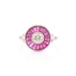 A diamond and ruby target ring, in the Art Deco style, centred with a round brilliant-cut diamond,