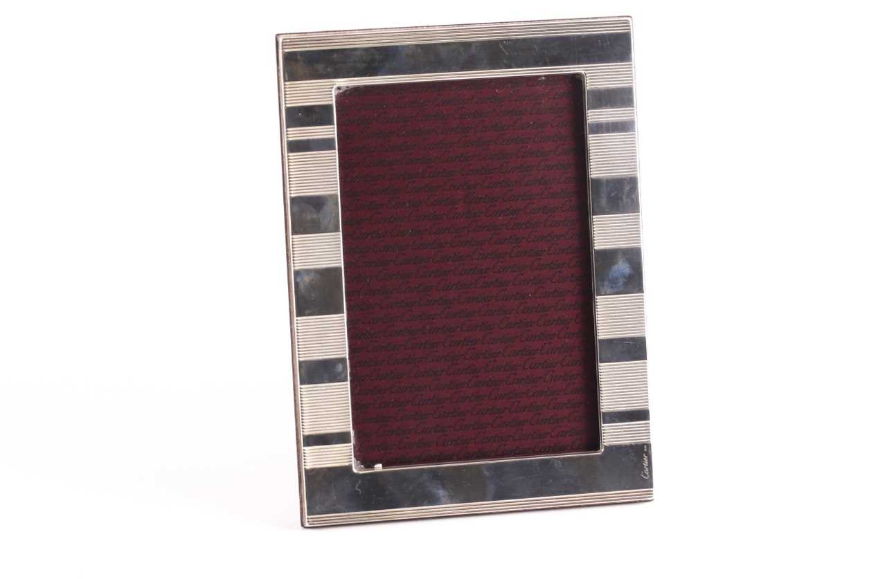 Cartier. A silver photograph frame; rounded rectangular with horizontally banded decoration.
