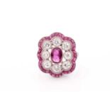 A platinum, diamond, and ruby ring, the stylised mount centred with a mixed oval-cut ruby within a