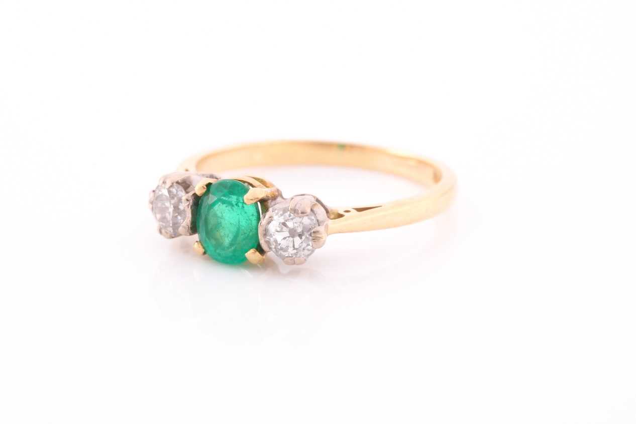 A three stone half hoop emerald and diamond ring. The oval cut emerald in four claw mount flanked by - Image 2 of 4