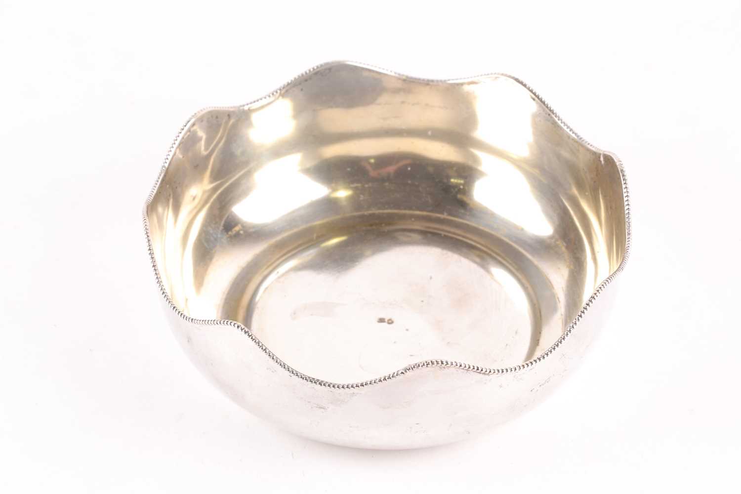 A 20th-century circular white metal fruit bowl with a serpentine beaded rim. Bearing indistinct - Image 2 of 4