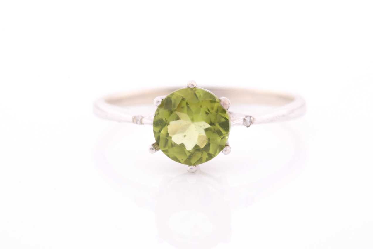 A peridot and diamond ring, centred with a mixed round-cut peridot, approximately 7.6 mm diameter,