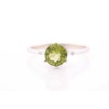 A peridot and diamond ring, centred with a mixed round-cut peridot, approximately 7.6 mm diameter,