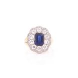 A yellow metal, sapphire, and diamond cocktail ring, set with a rectangular-cut sapphire, within a