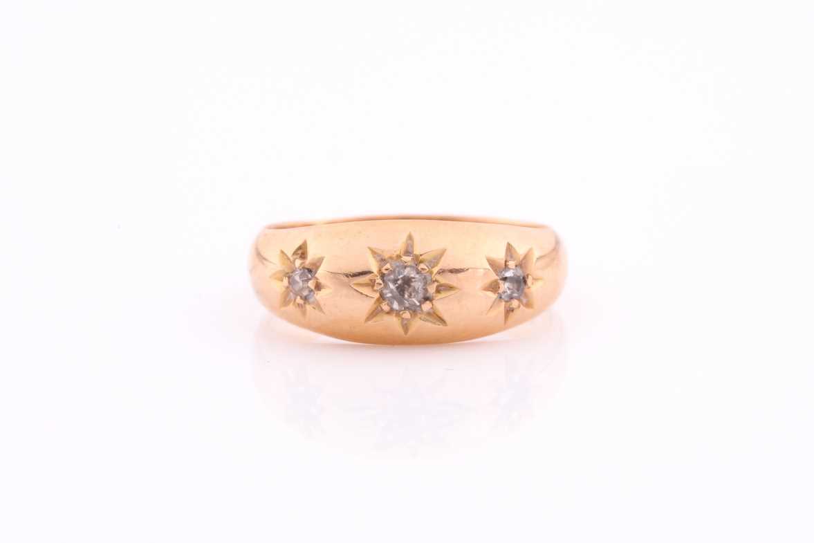 A three stone gypsy set ring, the graduated old brilliant cut diamonds in tapering 18 carat rose