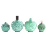 A collection of four carved and moulded green glass scent bottles; carved with scenes from rural