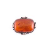 An Art Nouveau silver and amber brooch, the large rectangular single stone amber plaque withing an